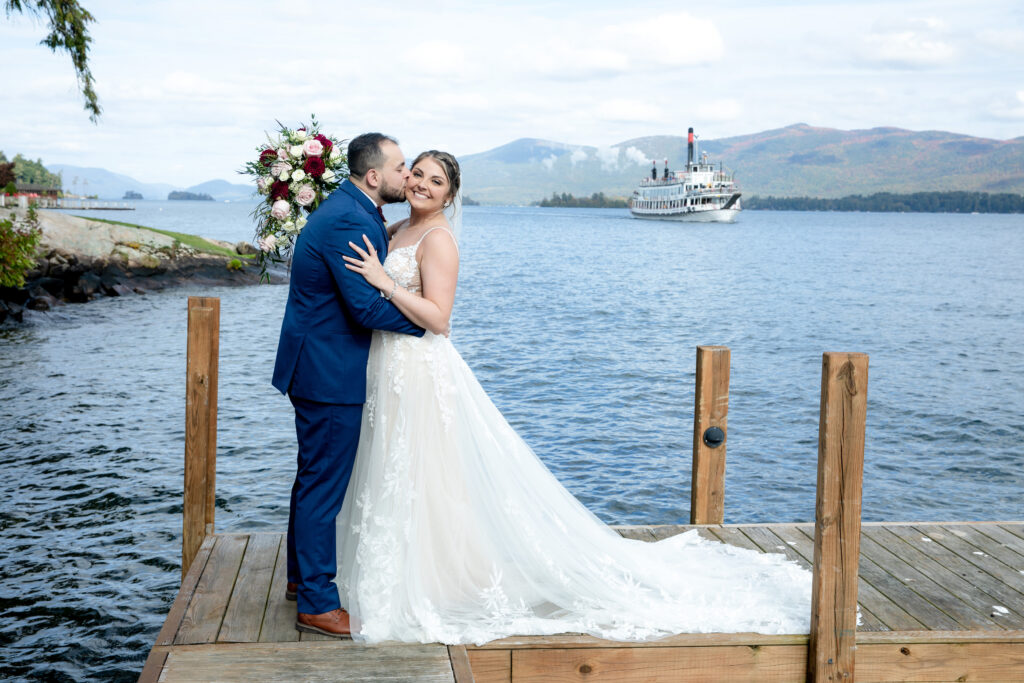 Newlyweds waiving to boat on lake george from a wedding in lake george at the Inn at erlowest