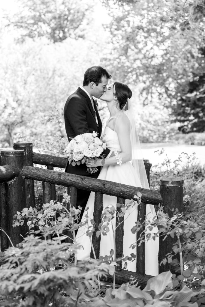 The lovely new married couple sharing a kiss in the spring foliage.