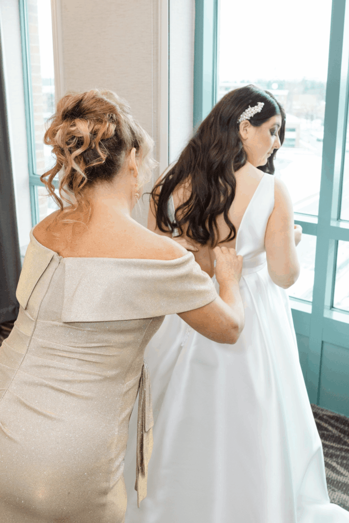 Mother and Bride getting ready for the ceremony. Mother is helping zip the brides gown.